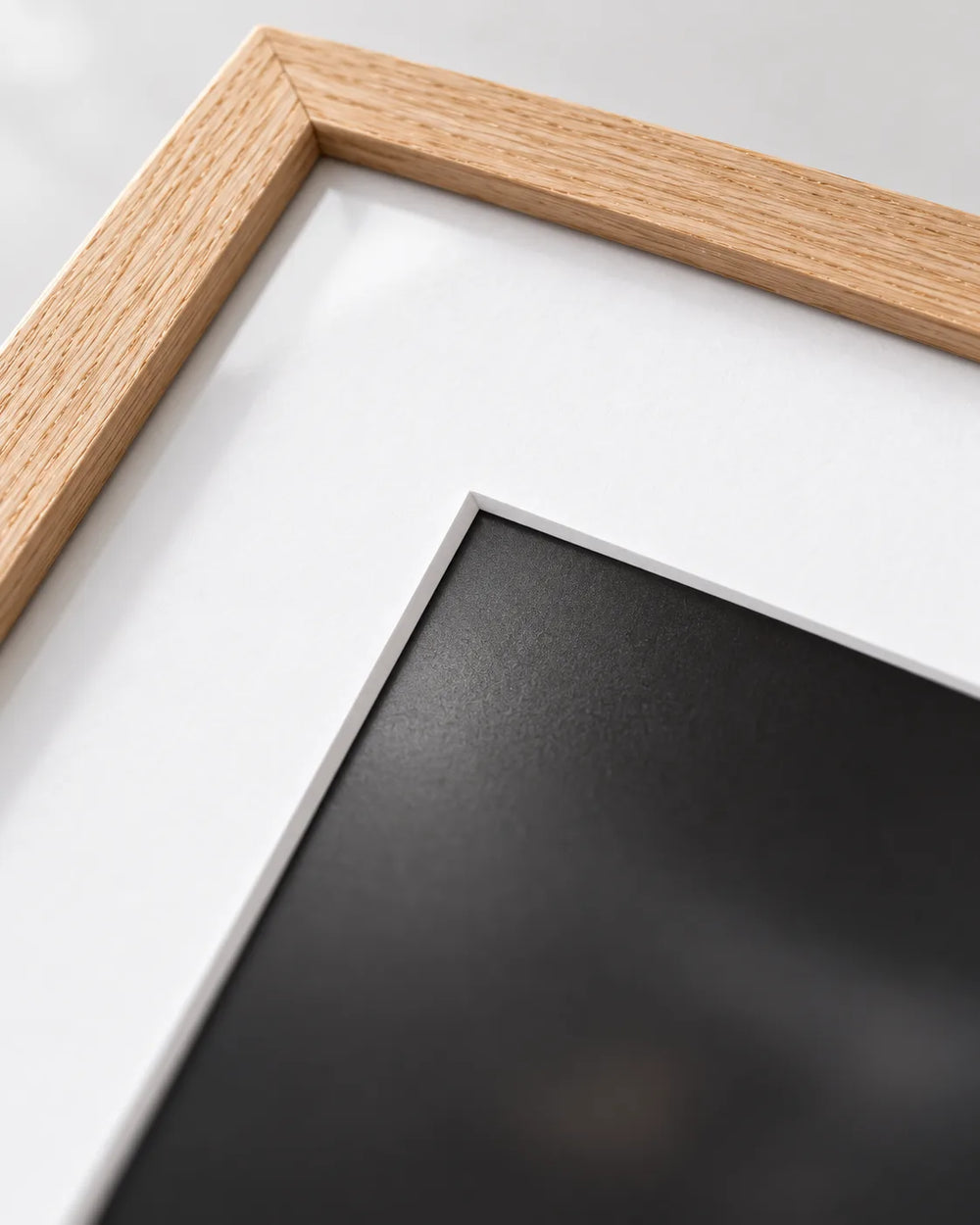 Bright white mat with bevelled opening inside a natural oak frame