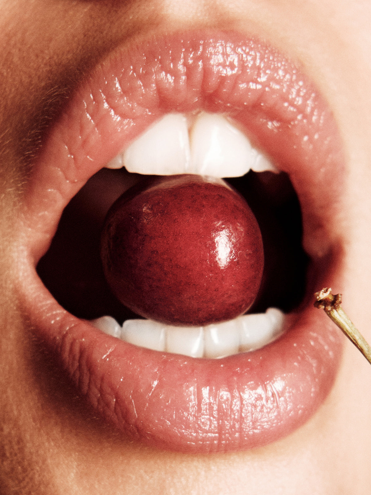 Cherry by Josy Graye, close-up of glossed lips holding a dark red cherry