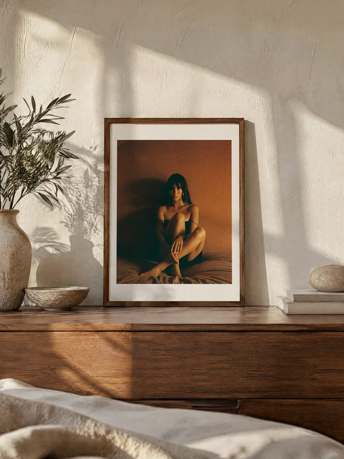 Terracotta Portrait by Wam Ornelas, framed in walnut oak with a white mat (18 × 24 in), leaning on a wooden dresser