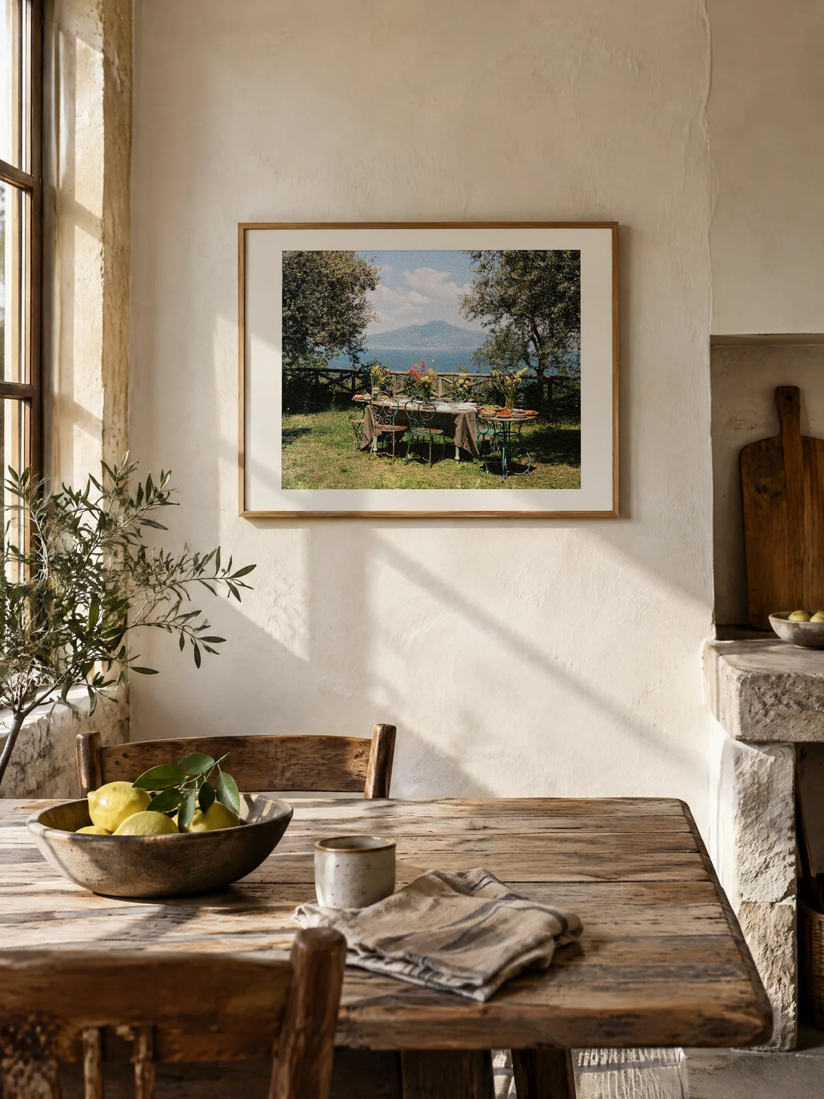 Under the Trees by Wam Ornelas, framed in natural oak with a white mat (24 × 18 in), above a kitchen table