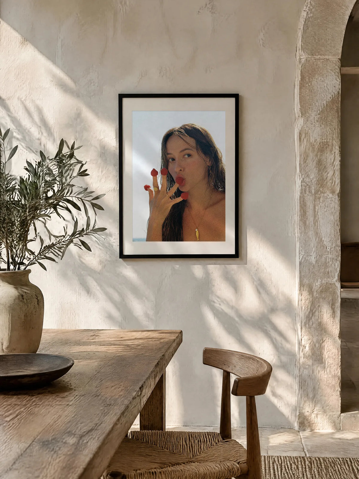 Raspberries by Wam Ornelas, framed in black oak with a white mat (24 × 32 in), above a wooden table